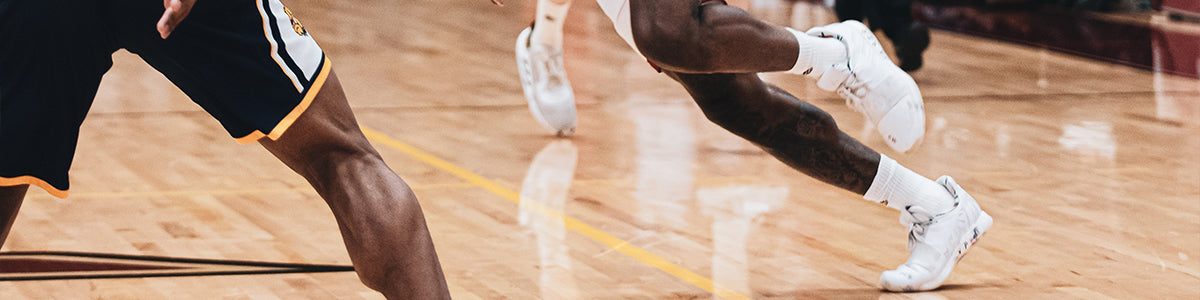 Closeup of man wearing white basketball shoes playing on a basketball court