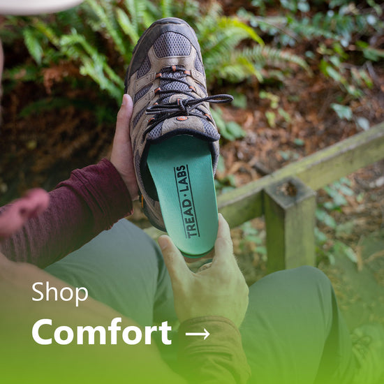 A person sliding a green Ramble insole into a hiking shoe.