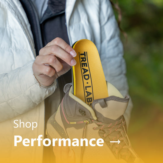 A woman sliding a yellow Dash insole into a hiking boot.