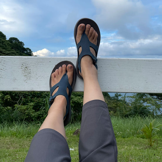 POV of woman wearing blue Albion Sandals resting her feet on a white fence