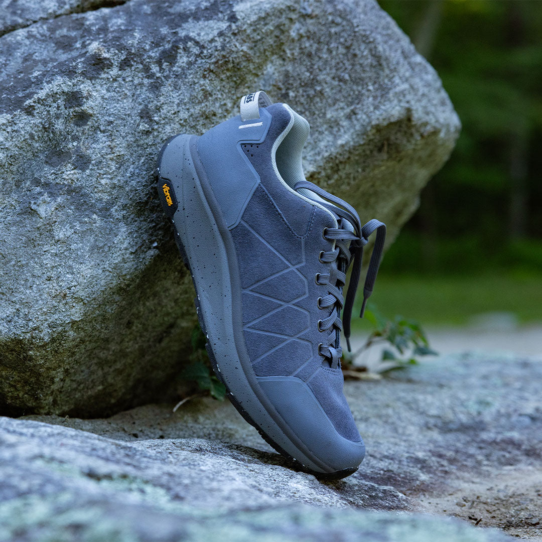 Blue athletic shoe leaning against a rock outdoors