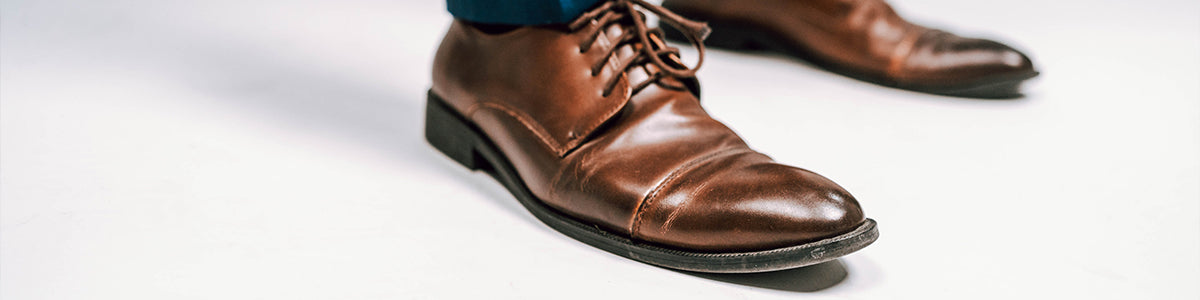 Closeup of men's brown leather dress shoes on a white background