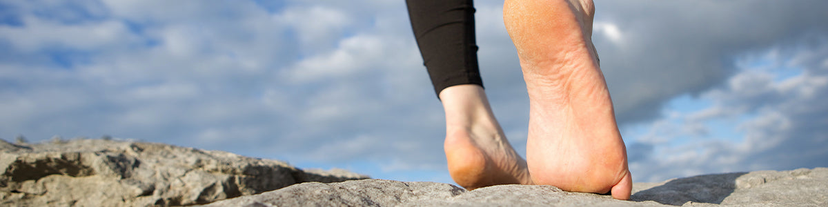 A person with high arches walking across stones