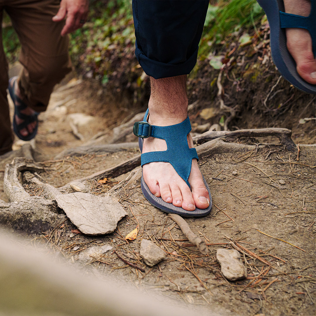 Man wearing Albion Sandals hiking up a trail in the forest
