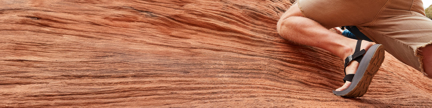 Man hiking up red rocks in Utah wearing black Men's Albion Sandals