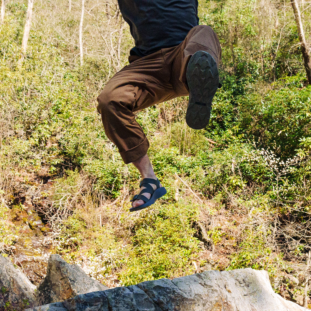 Man wearing Redway Sandals jumping off a rock cliff