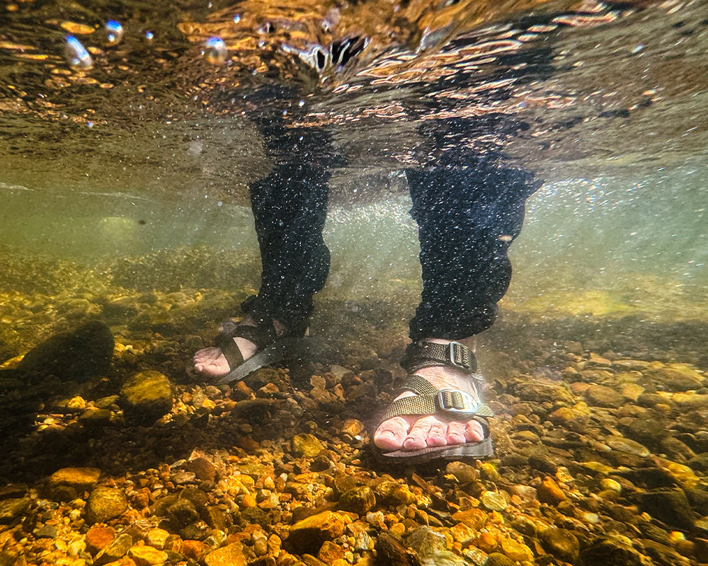 Underwater shot of man wearing Redway sandals on a rocky riverbed