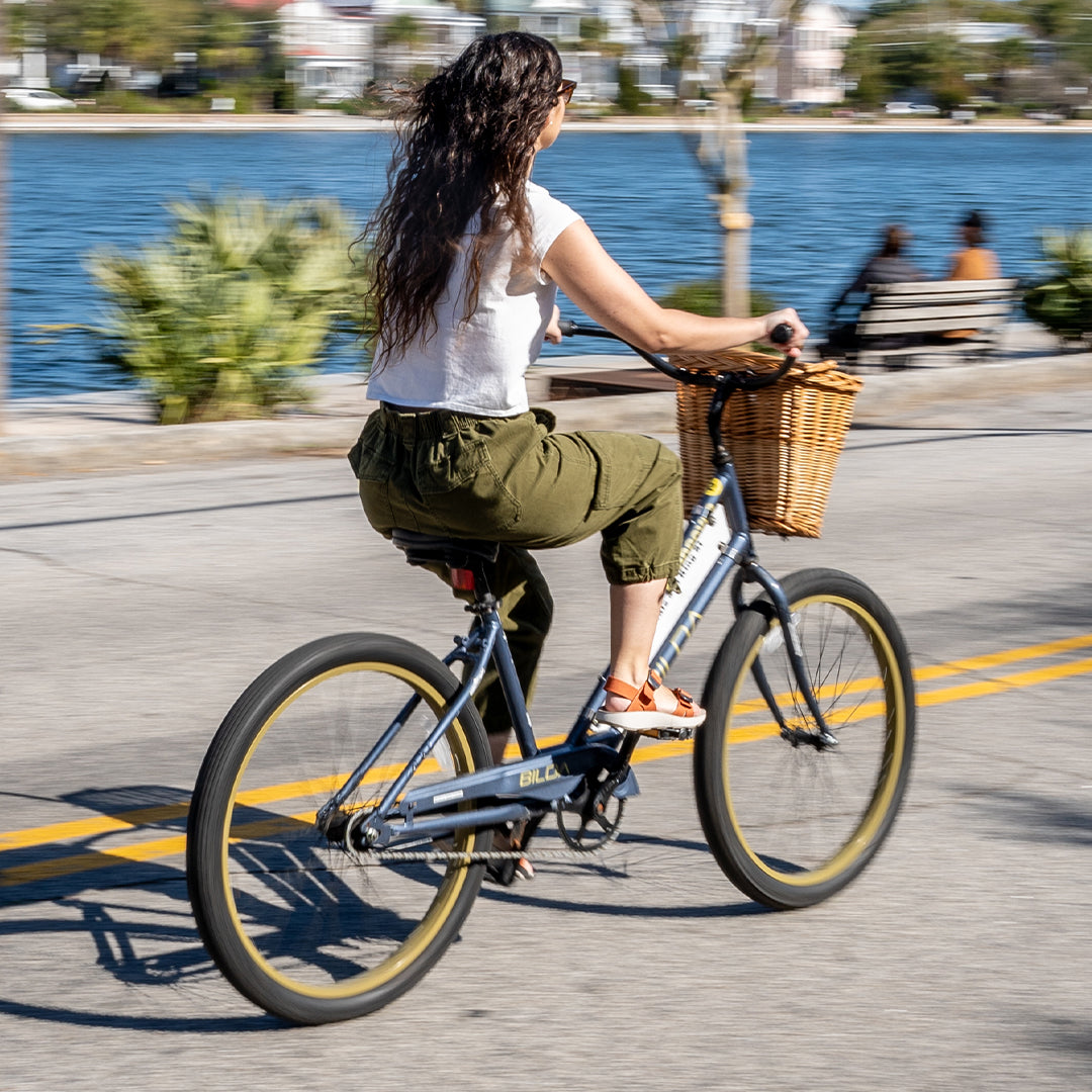 Woman riding a bicycle on the road wearing orange Salinas sandals.