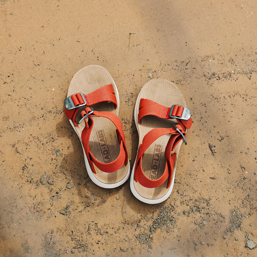 Salinas Sandals in Apricot on a sandy bank.