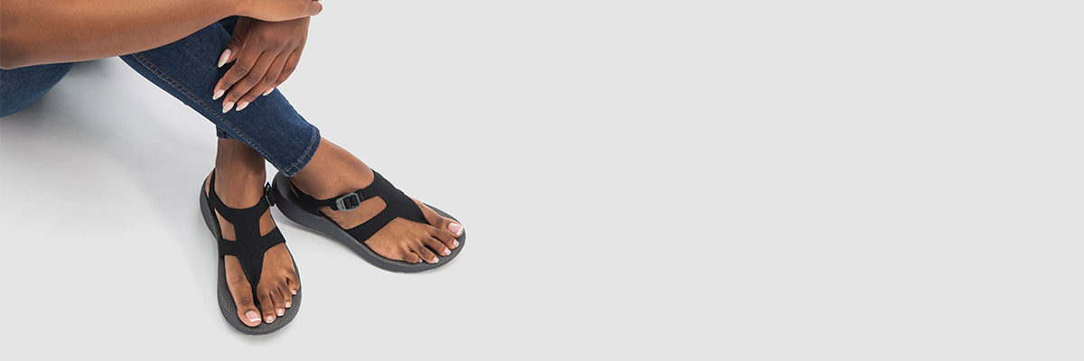 A close up of a woman's feet in black Albion sandals.