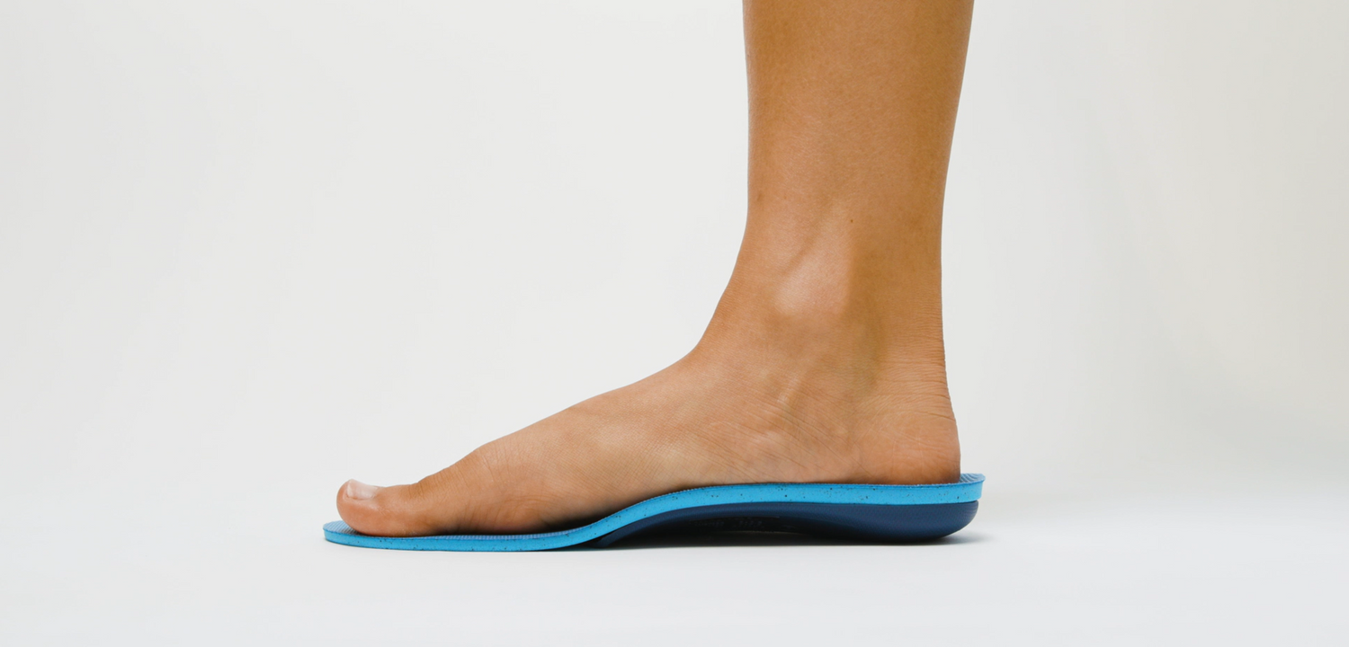Person's foot on top of a Tread Labs arch support insole on a white background.