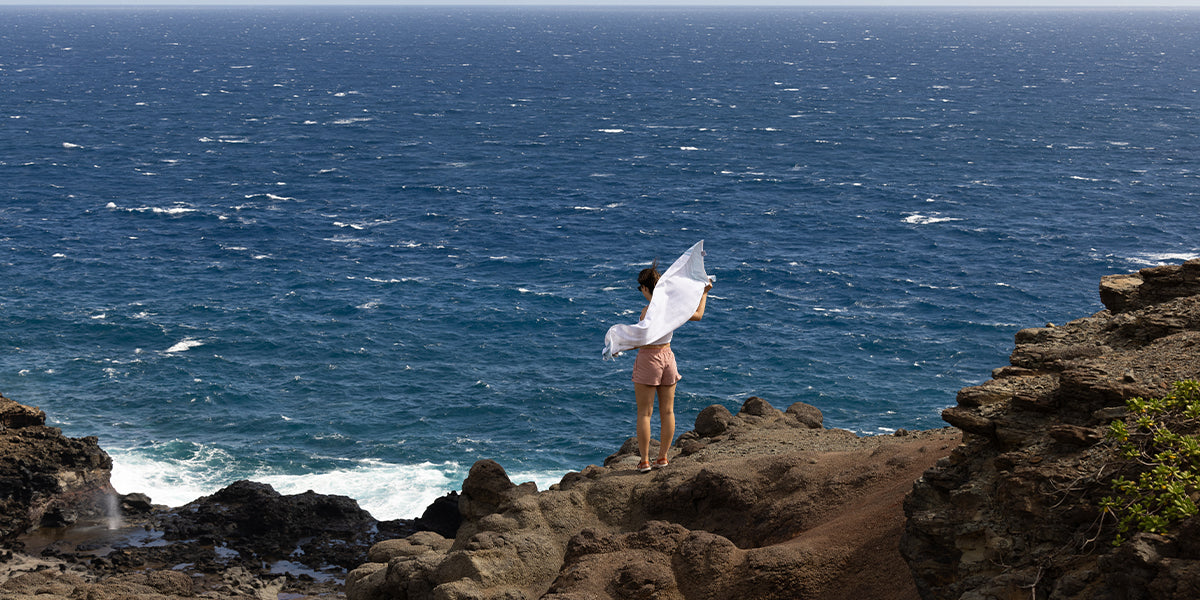 Woman wearing Salinas Sandals standing on a rocky ledge overlooking the ocean