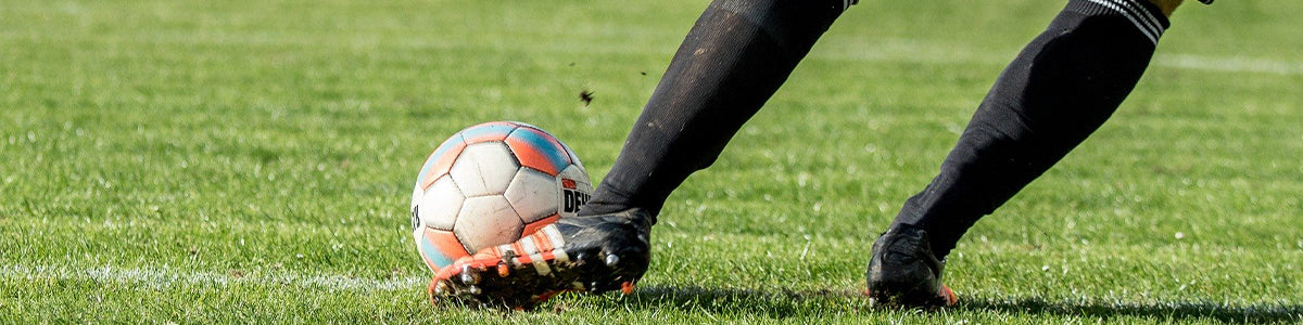 Closeup of soccer player wearing insoles for cleats kicking a soccer ball