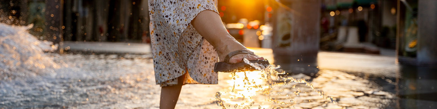 Woman wearing Tread Labs flip flops dancing in a fountain at sunset