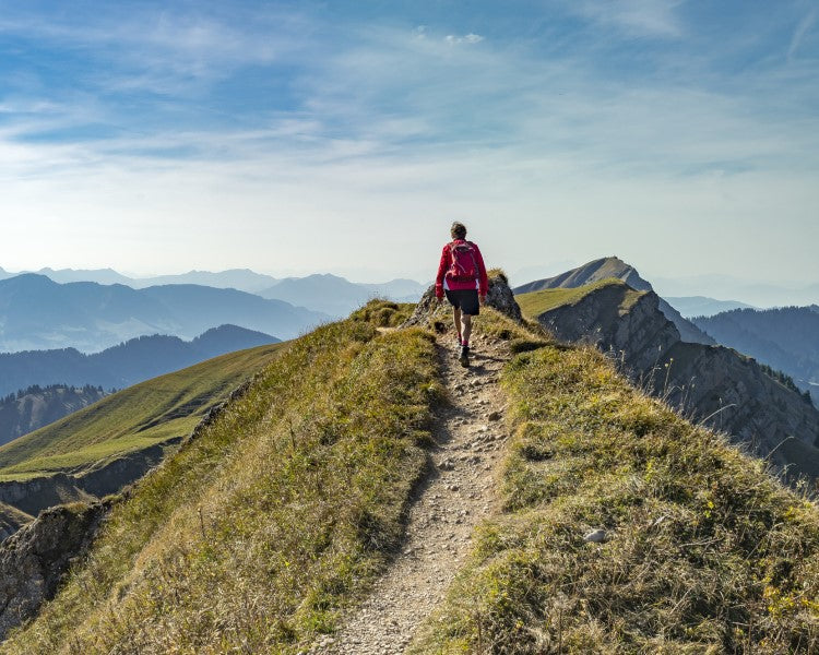 Man hiking up single track trail with a mountain view