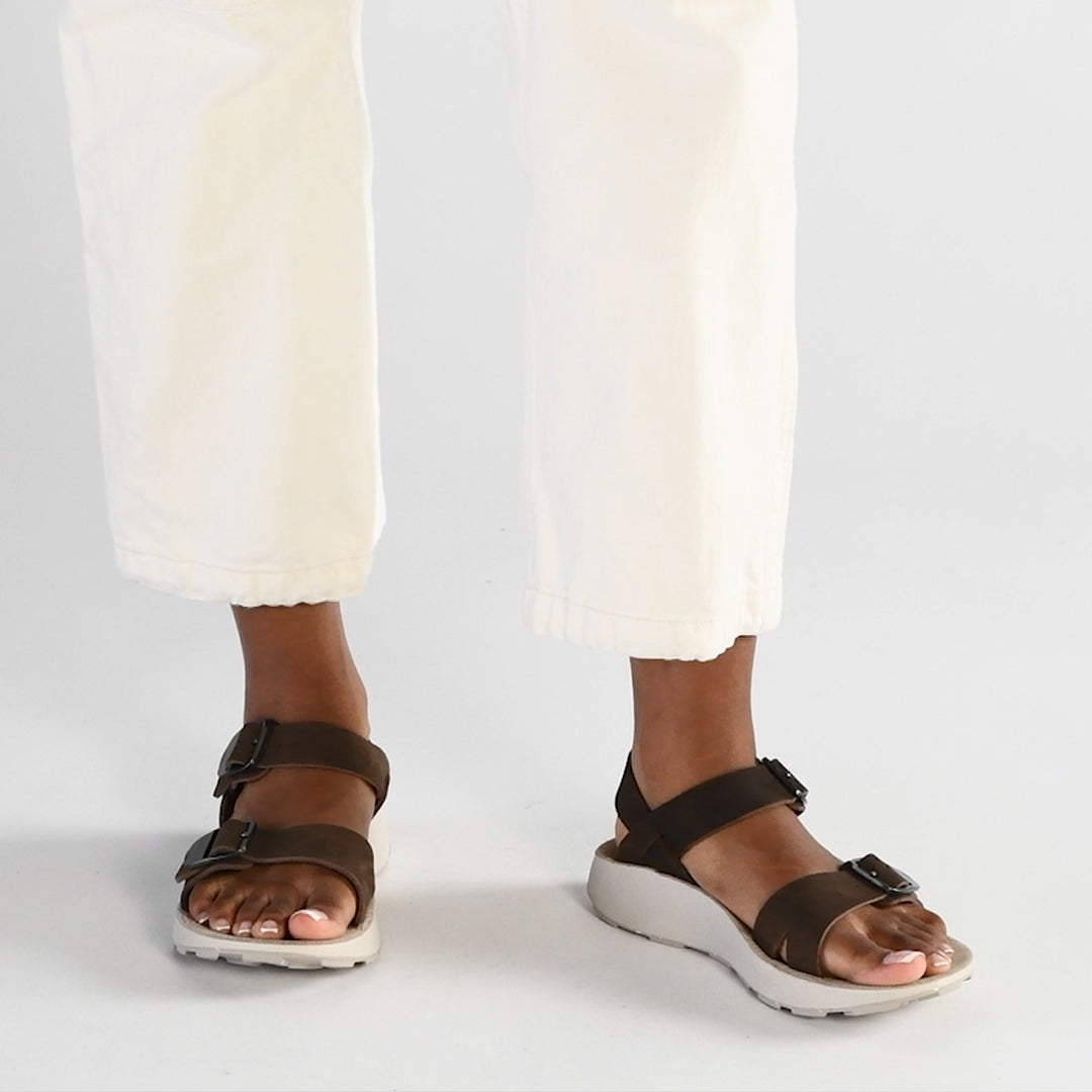 Female model walking across white background with Salinas Leather Sandals in Havana