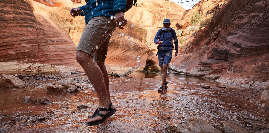 Two backpackers in a desert stream wearing Tread Labs sandals