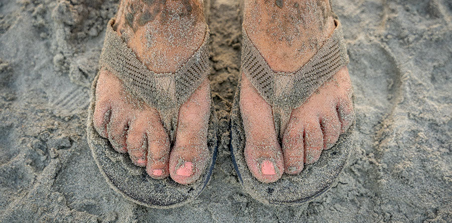 Sandy feet in flip flops.