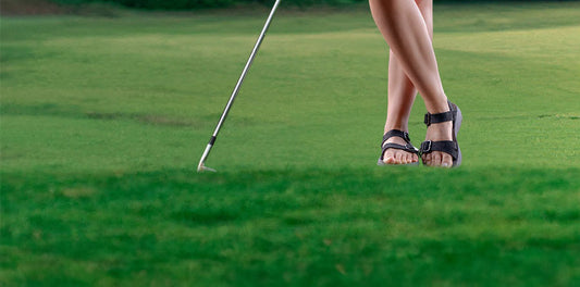 Women's bare legs and feet showing, wearing Tread Labs Salinas Leathe sandals on a golf course.