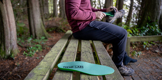 Man inserting an insole into a boot, with a tread labs insole in the foreground.