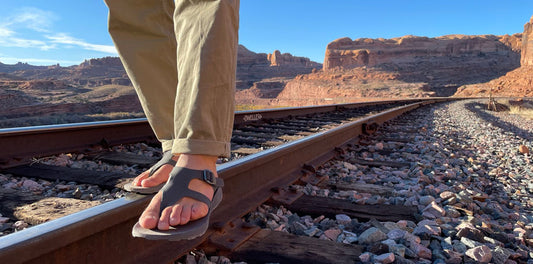 man walking on rail track in sandals