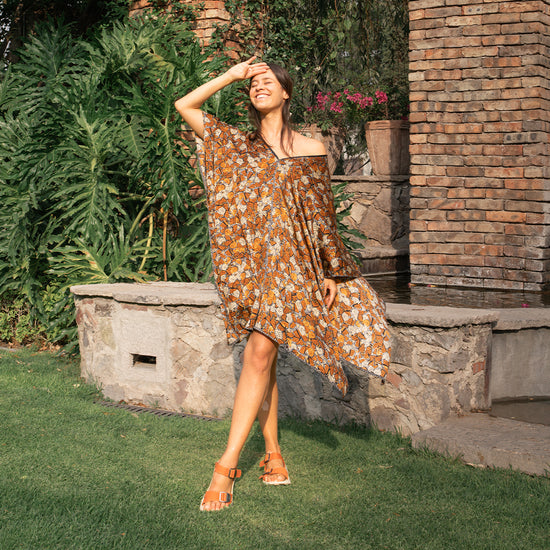 Woman wearing a flowing dress and orange Salinas Sandals posing by a colonial Mexican home at sunset.