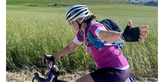 Woman cycling by a green field