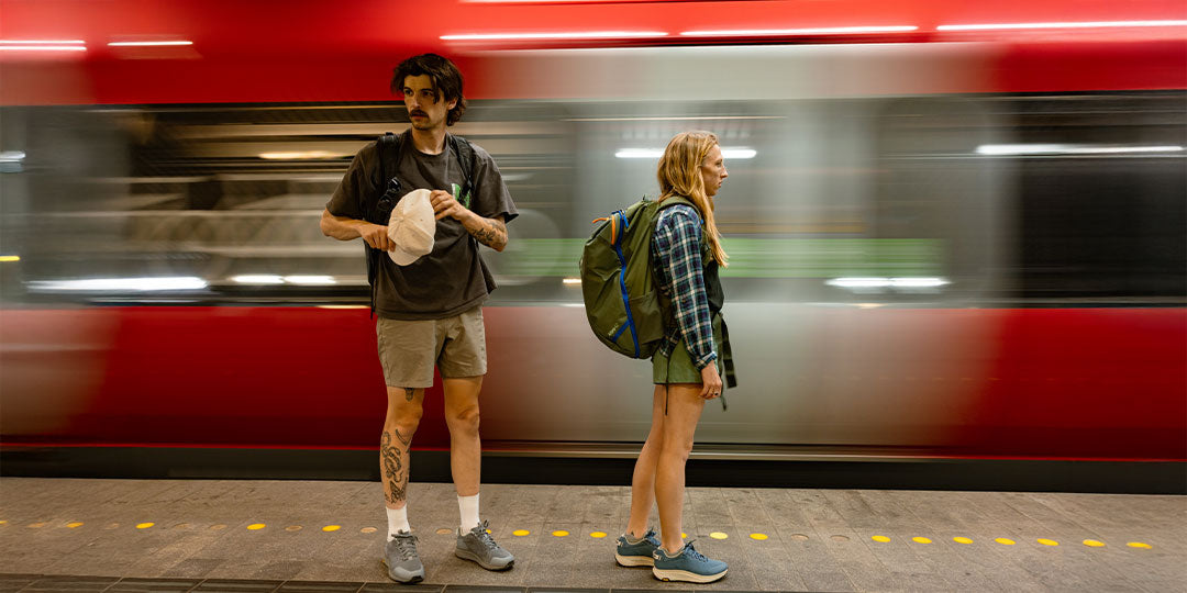 Two people standing on a train platform with a blurred train in the background