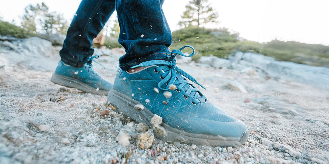 Blue hiking boots on a rocky trail with a natural background