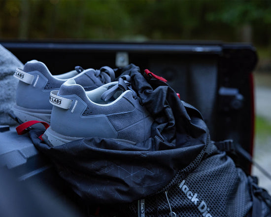 Gray hiking shoes in a black backpack in an outdoor setting