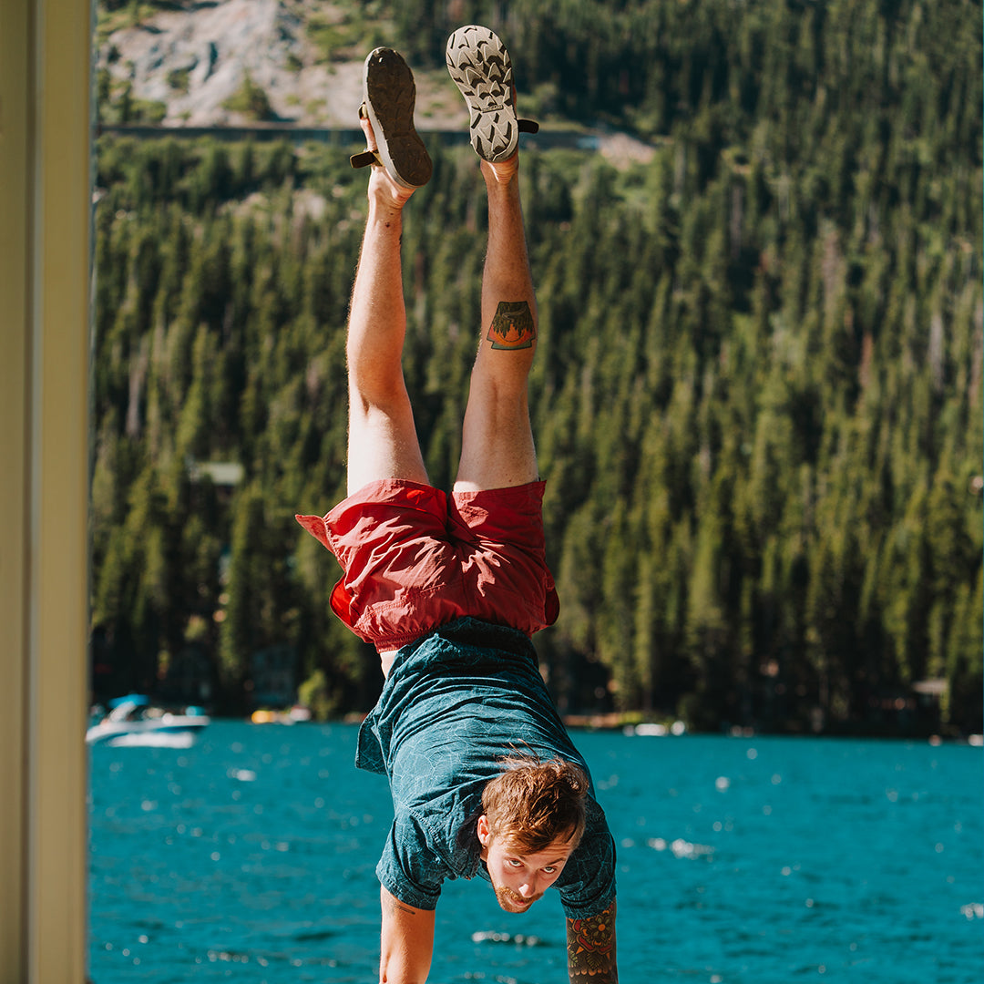 Man wearing Redway Slide sandals doing a handstand on a dock by a lake.