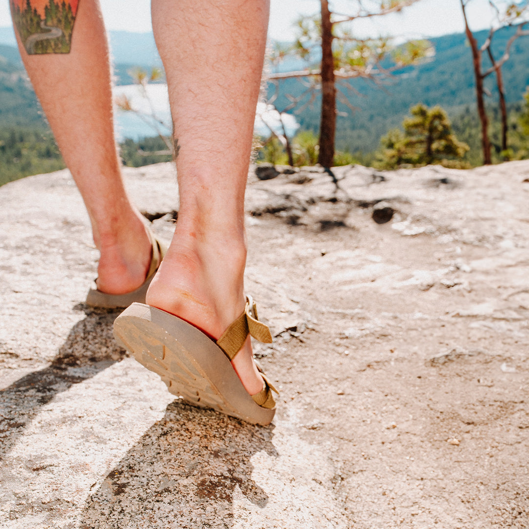 Man wearing Redway Slide Sandals walking along a cliff overlooking a lake.