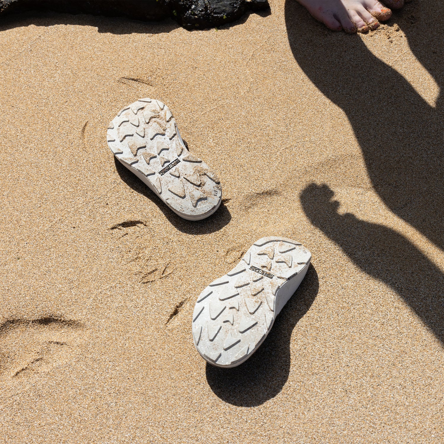 A pair of Orleans Leather sandals displayed on the sand at a beach