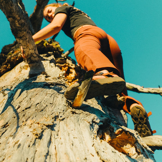 Woman wearing Redway Sandals climbing in a dead tree.