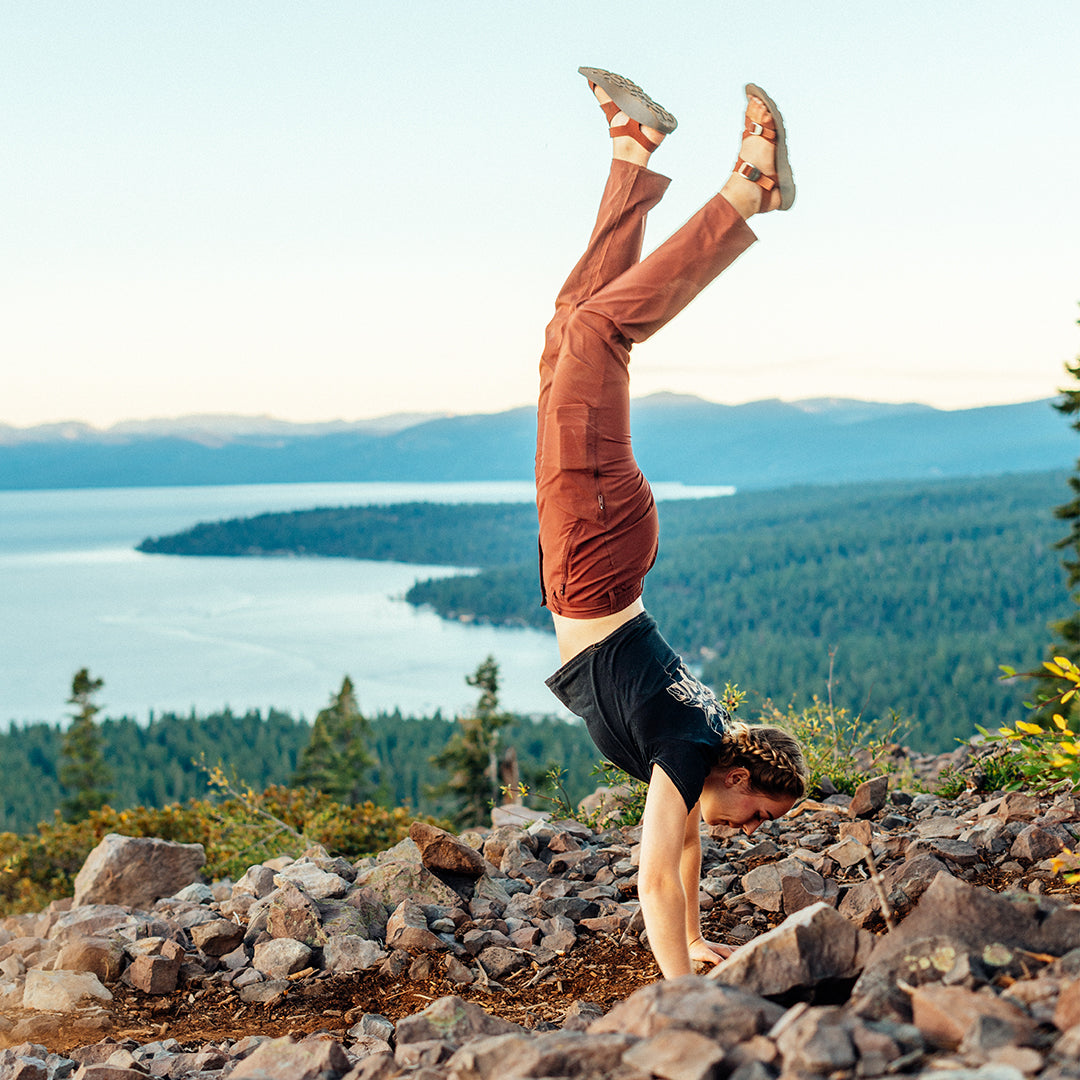 Woman wearing Tread Labs Redway Sandals doing a handstand on a cliff overlooking Lake Tahoe.