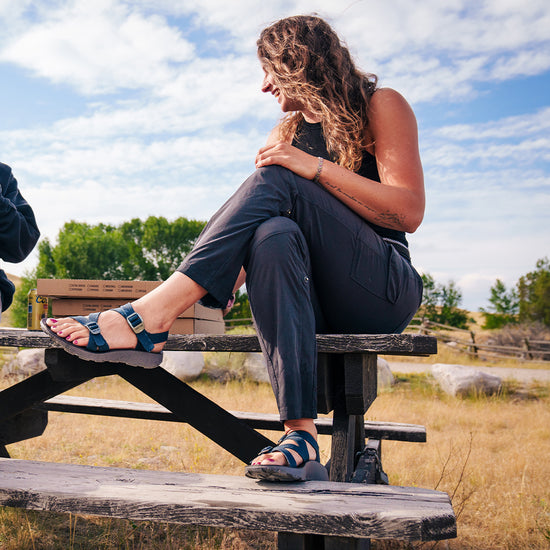 Woman wearing Tread Labs Redway Sandals sitting on a picnic bench.