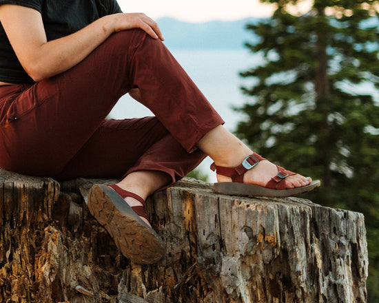 Woman wearing red Redway sandals sitting on a tree stump overlooking Lake Tahoe.