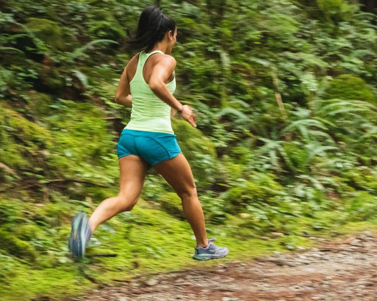 Woman running through lush trails 